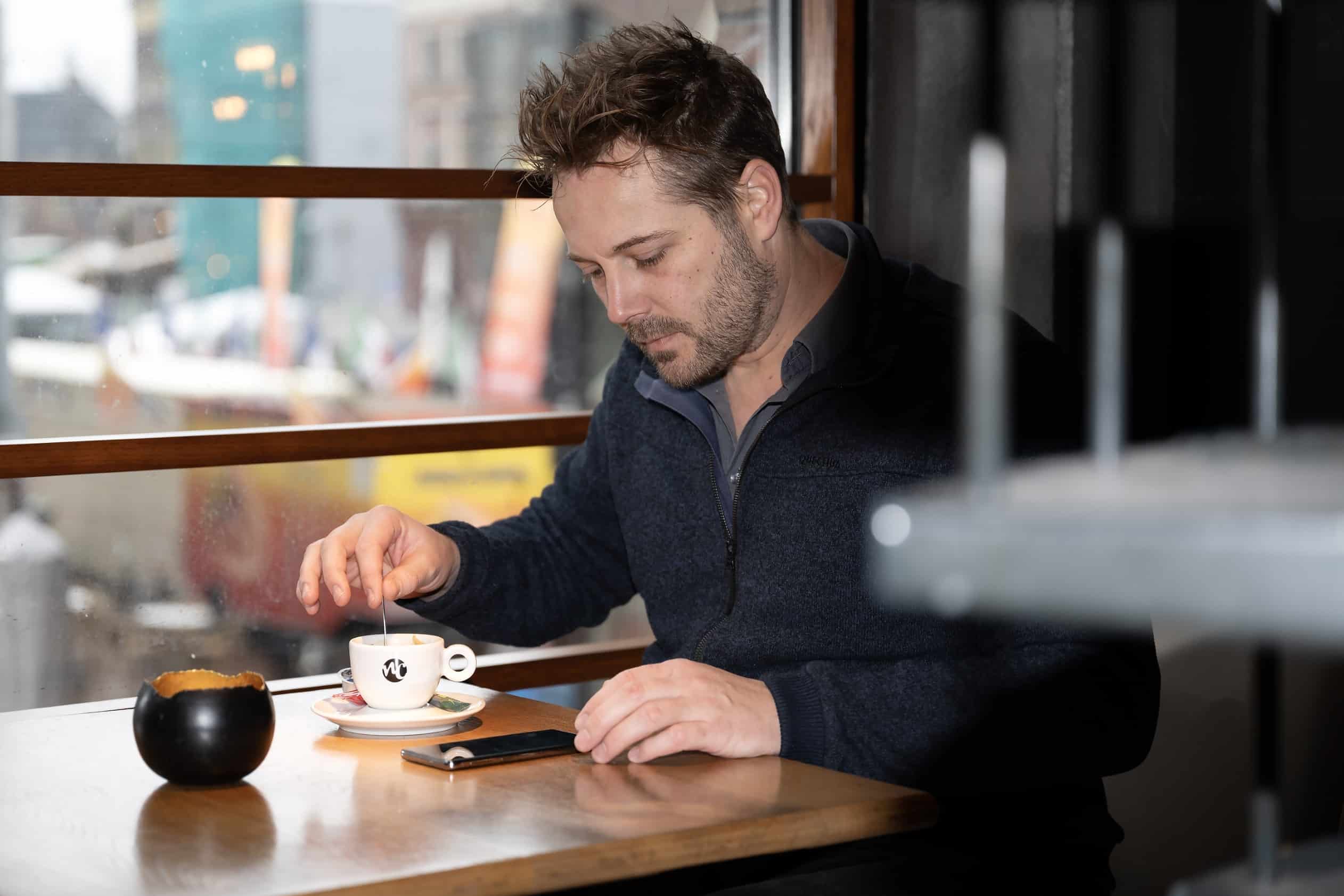 Foto van klant (Jons van der Heul) die zijn koffie roert.