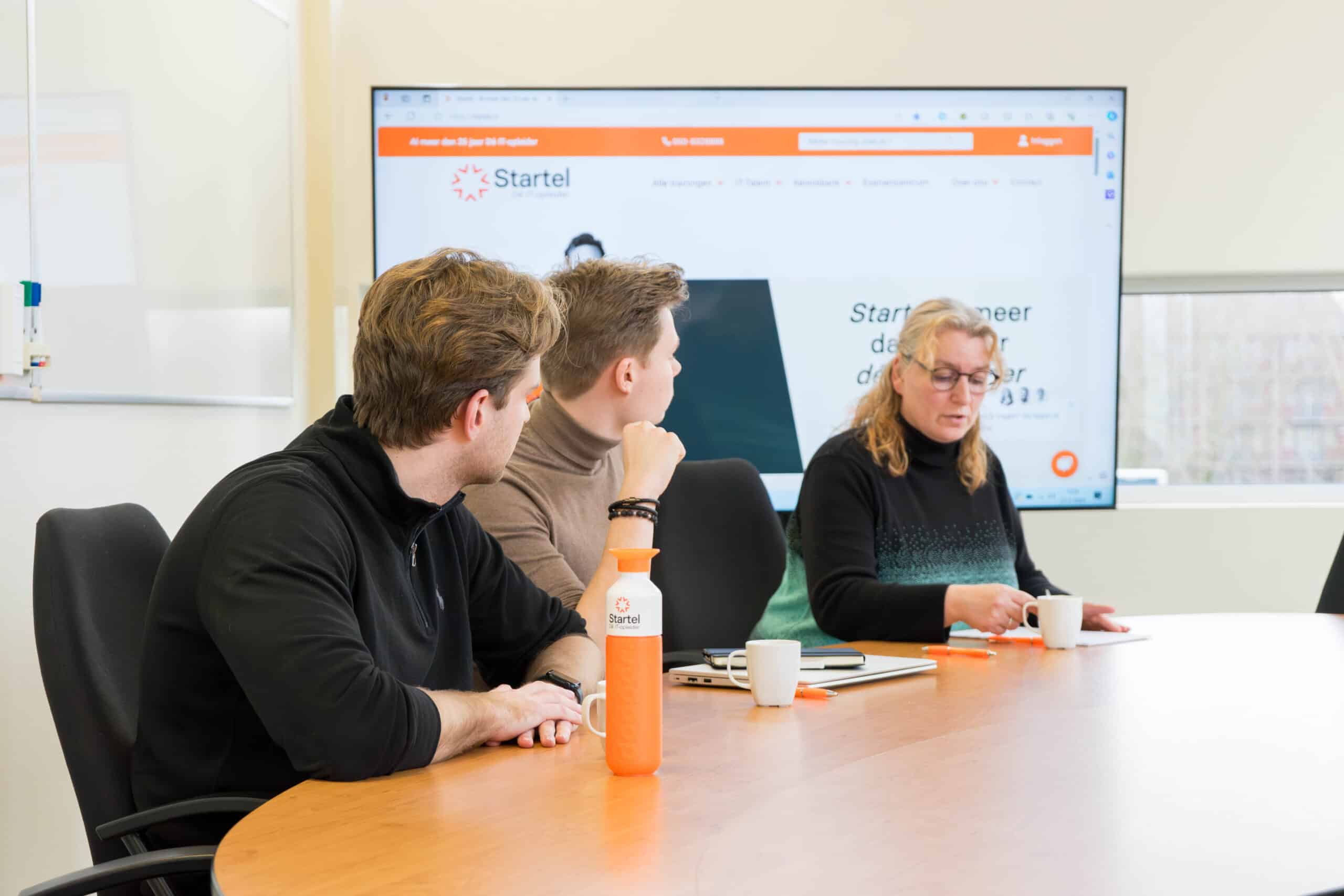 Een medewerker van Startel (Thea Plantinga) vertelt iets aan haar collega's.