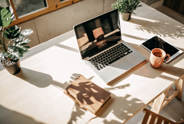 Foto van laptop, tablet en kopje op een bureau.